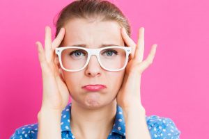 Young woman feeling stressed on a pink background